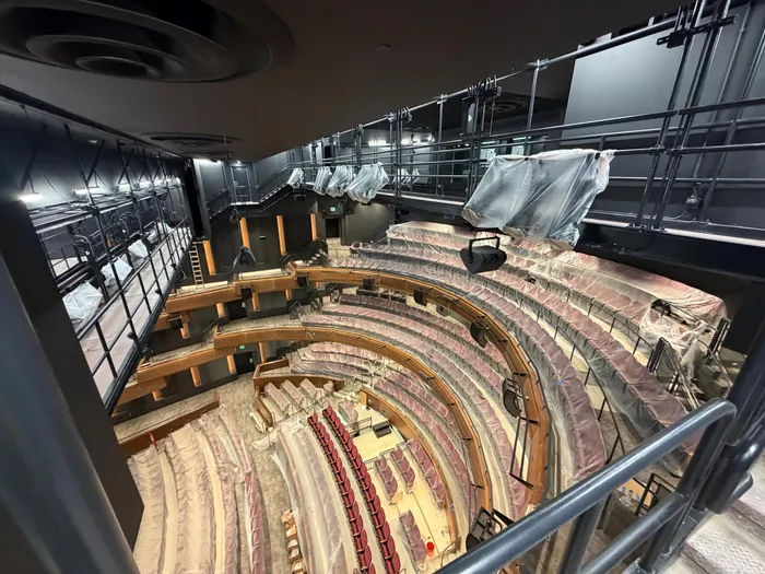 EBM crew member cleaning a wall along the theater aisle